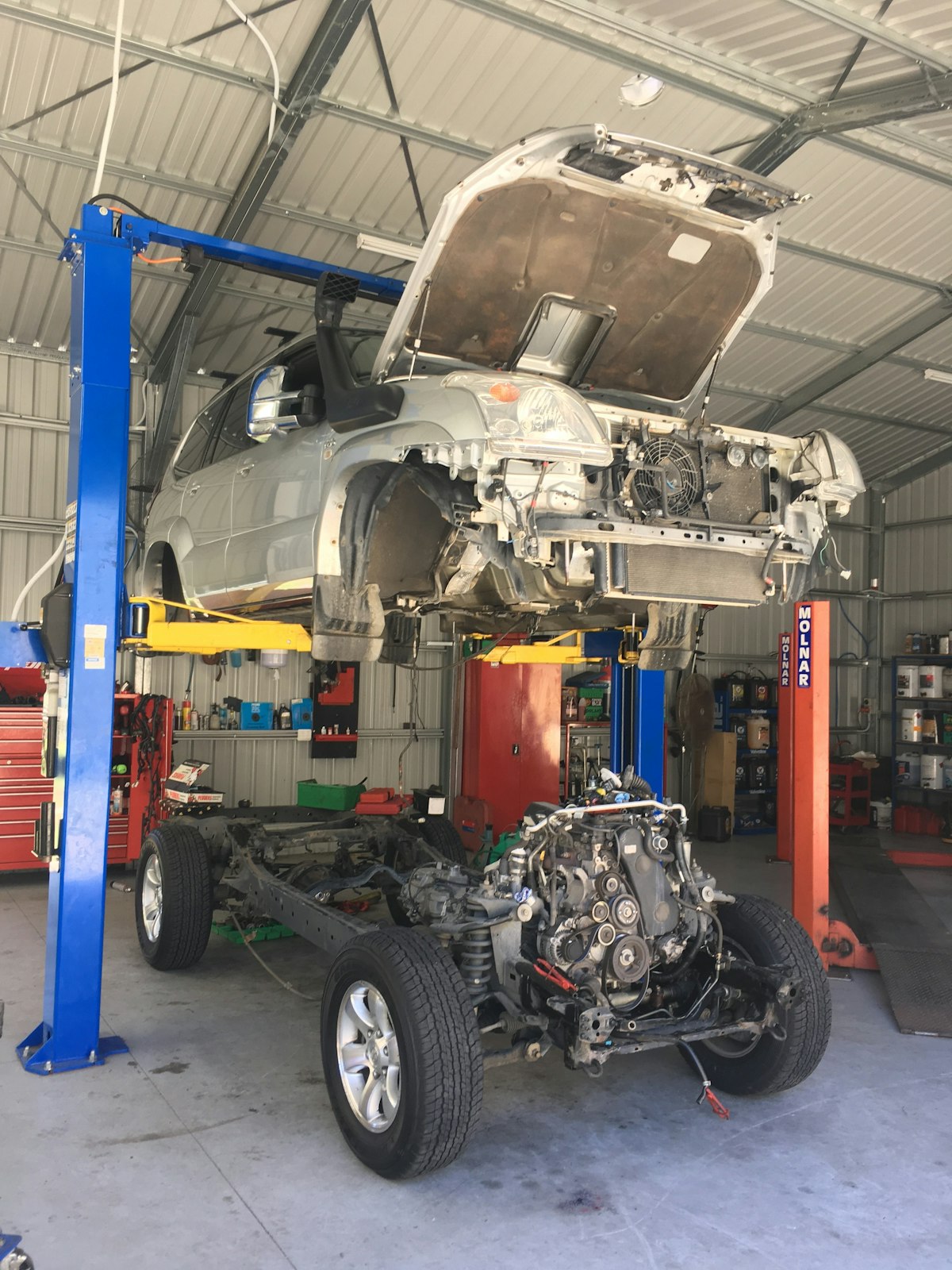 {{{businessName}}} mechanics replacing rusted underbody on Toyota Prado (front view).